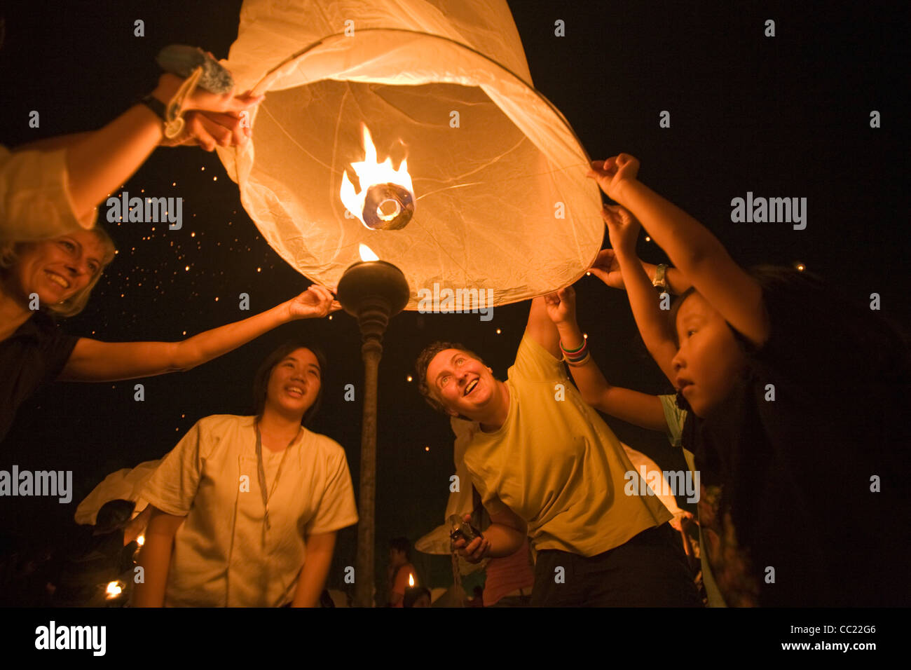 Revellers launching a khom loi (sky lantern) into the night sky during the Yi Peng festival.  San Sai, Chiang Mai, Thailand Stock Photo