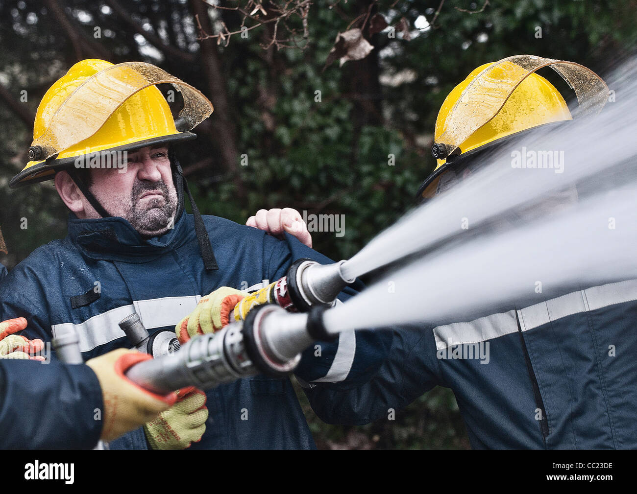 A fire fighter uses a water hose to douse a fire Stock Photo - Alamy