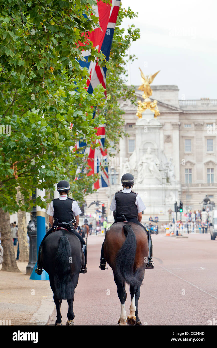 London polce officers riding horses on The Mall and marching towards Buckingham Palace. Stock Photo