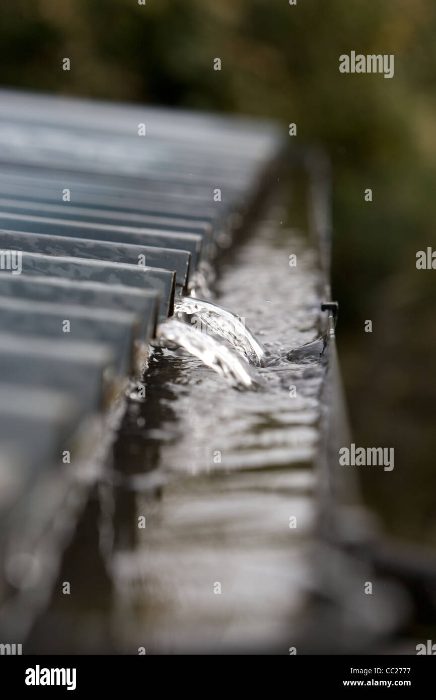 Rain water flowing in to a gutter from a corrugated roof Stock Photo