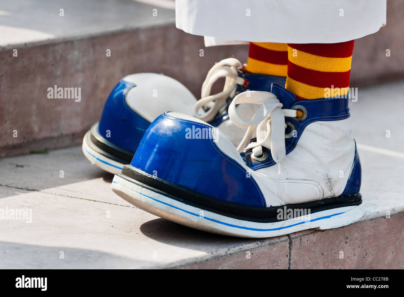 A clown wears oversized blue and white shoes during the Clown Congress in San Salvador, El Salvador. Stock Photo