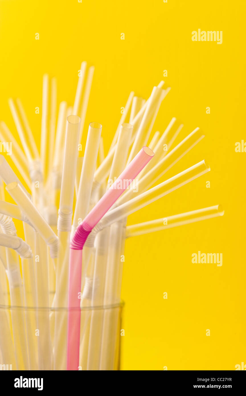 A pink straw amongst a group of clear straws Stock Photo