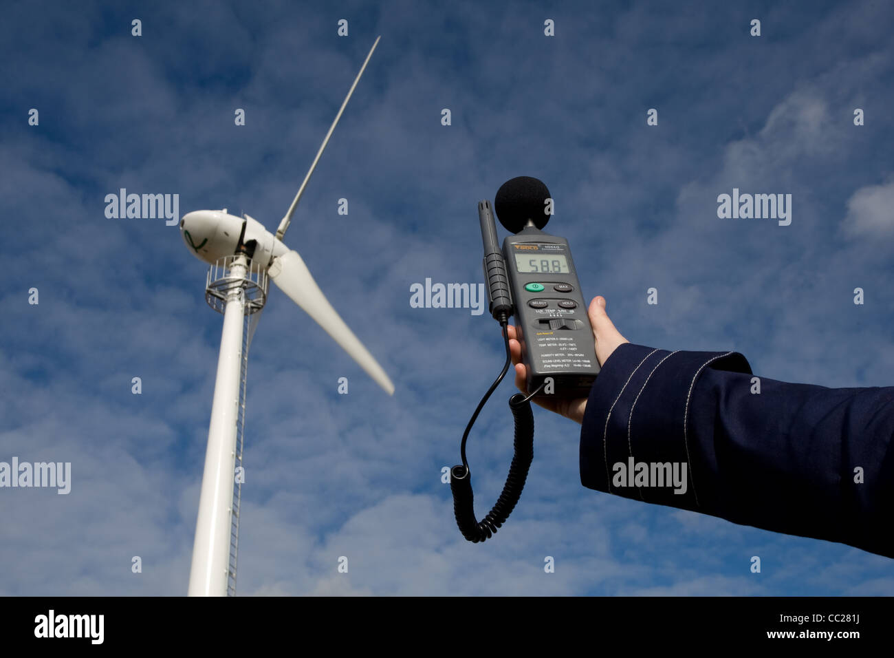 A sound level meter is held up to a wind turbine to measure the noise emitted in decibels Stock