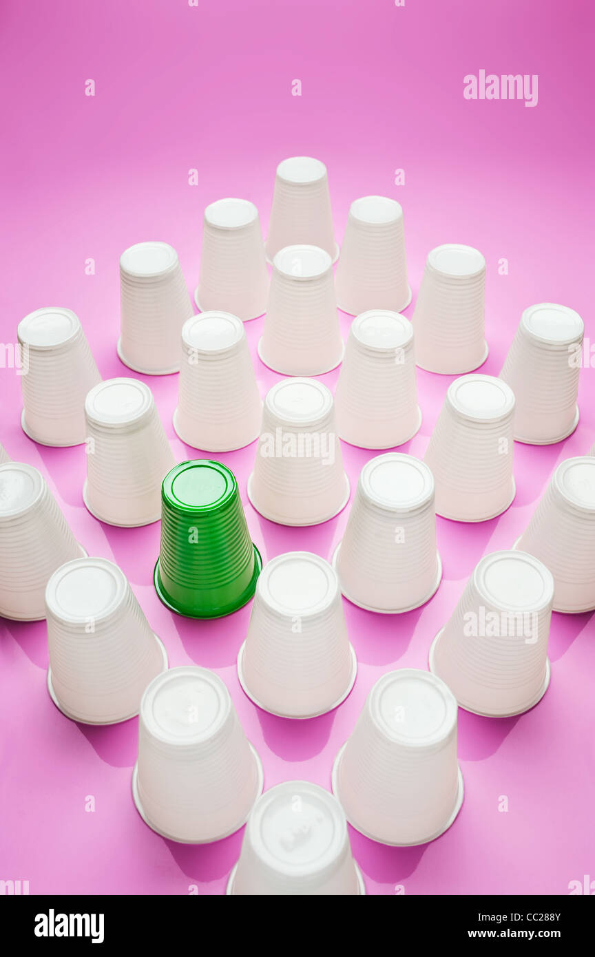 A green plastic cup amongst a group of white plastic cups Stock Photo