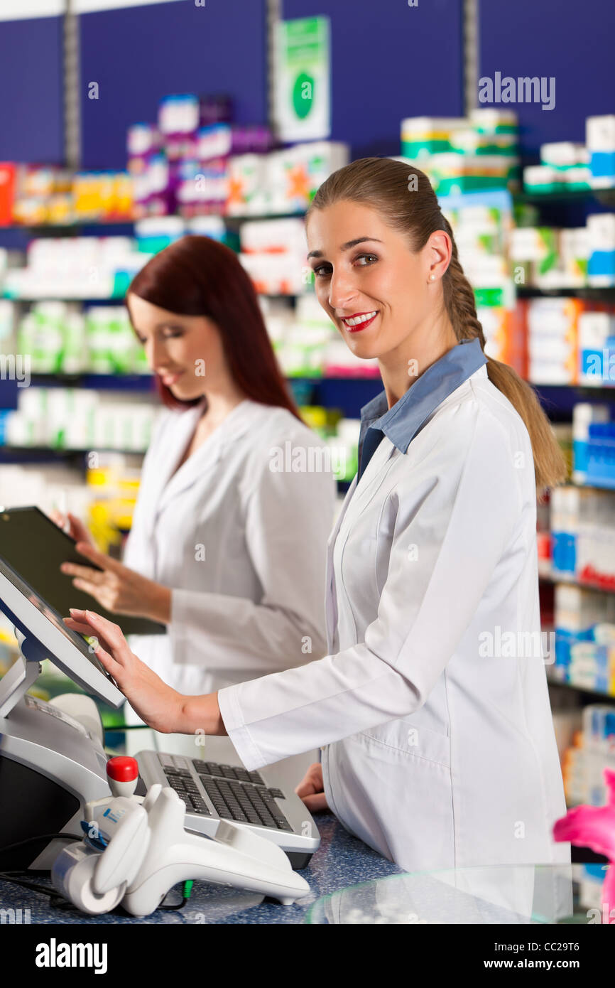 Pharmacist with female assistant in pharmacy standing at the cashpoint Stock Photo