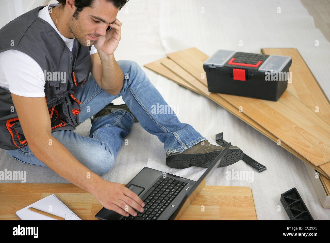 Man with laptop laying laminate flooring Stock Photo Alamy