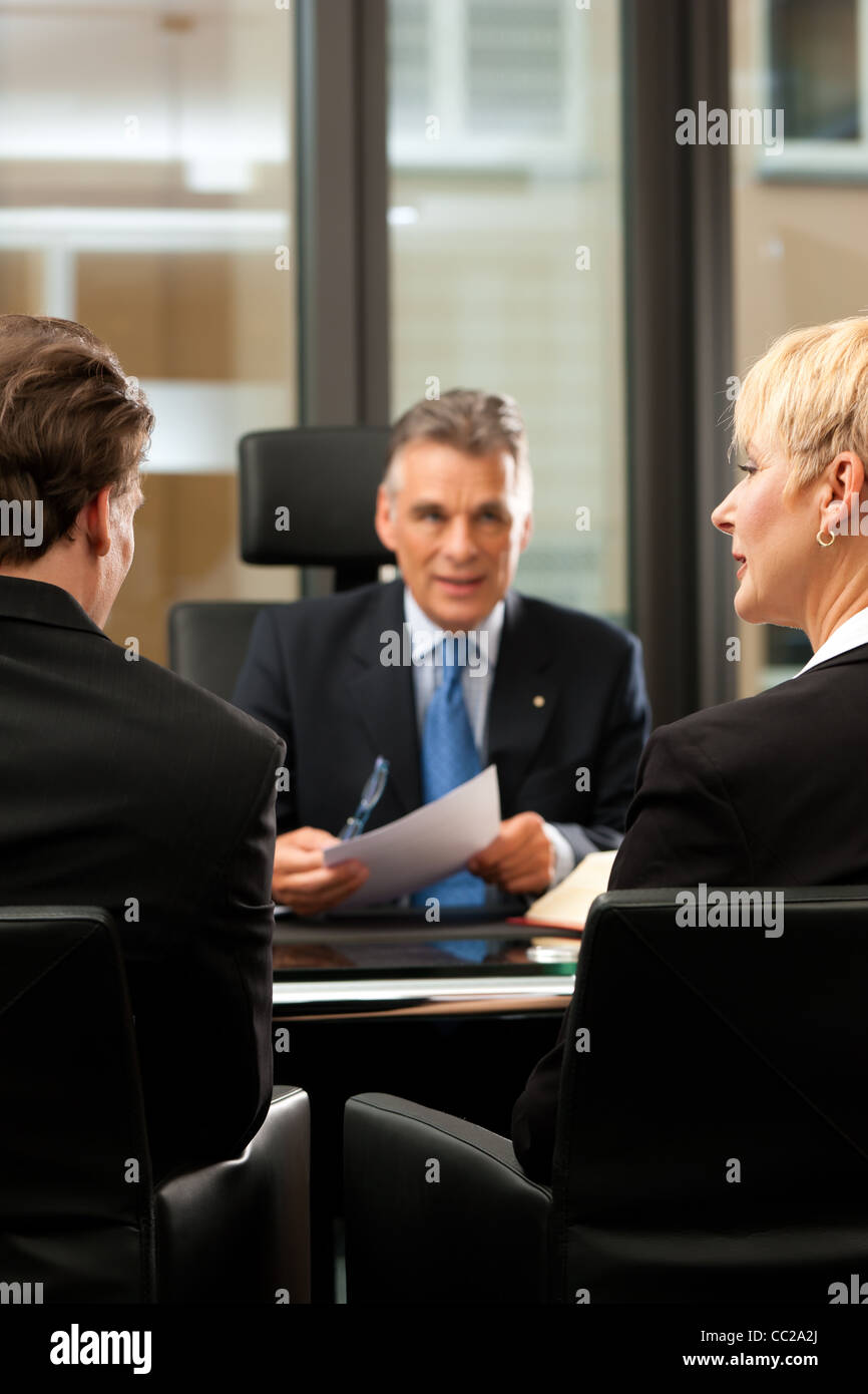 Mature lawyer or notary with clients in his office in a meeting Stock Photo