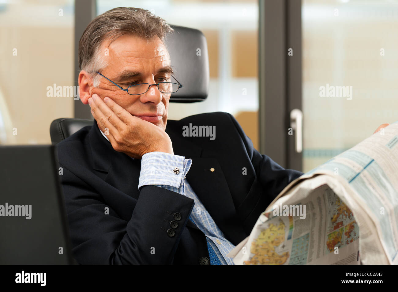Boss in his office reading newspaper the business section Stock Photo