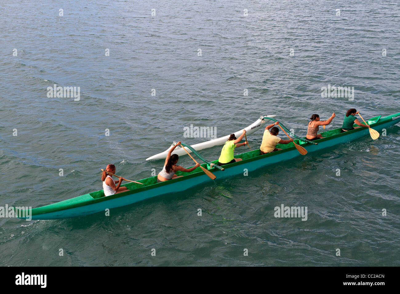Local youths paddle a traditional outrigger Hawaiian canoe in the