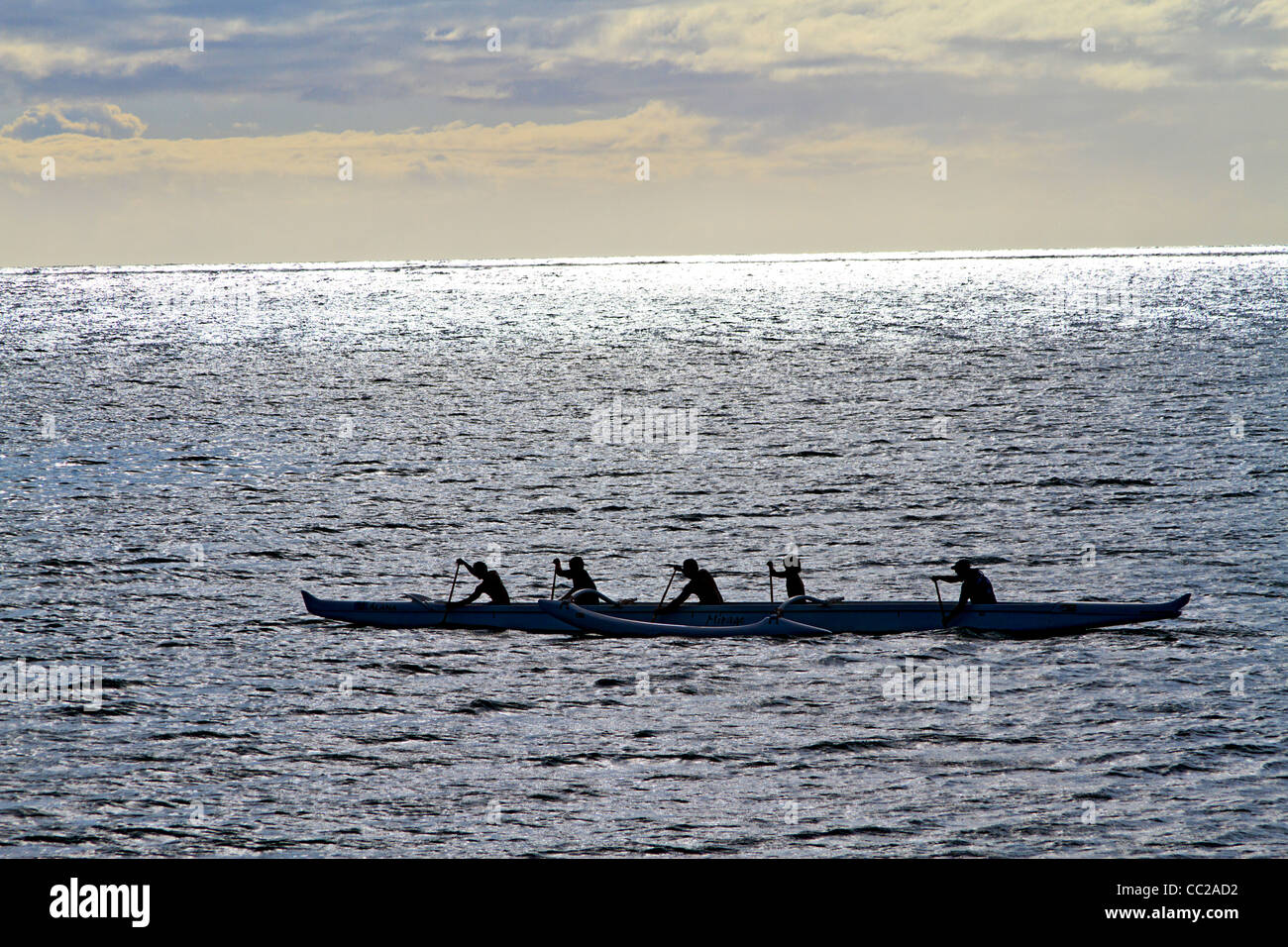 Local youths paddle a traditional outrigger Hawaiian canoe in the