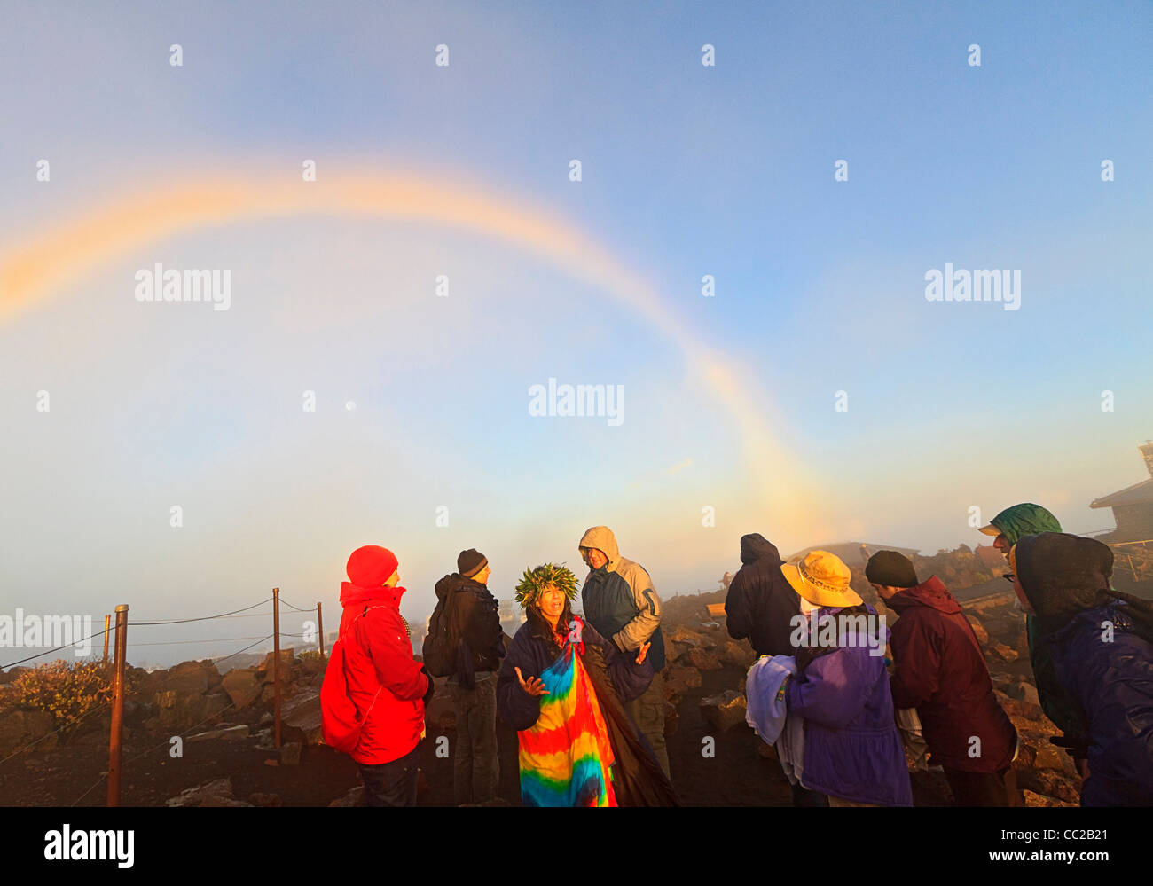 Barbara Bohonu, spiritual/cultural healer greeting sunrise and its rainbow with a chant at Haleakala Crater, Maui, Hawaii, USA. Stock Photo