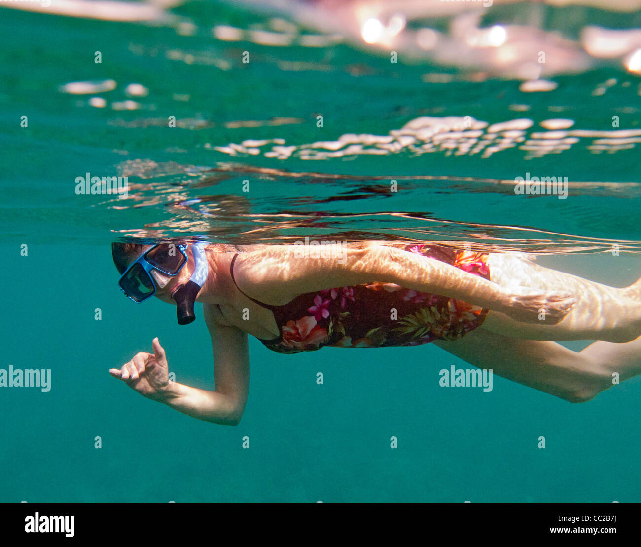 Woman gives 'shaka,' Hawaiian greeting sign while snorkeling in water off Maui, Hawaii, USA. Stock Photo