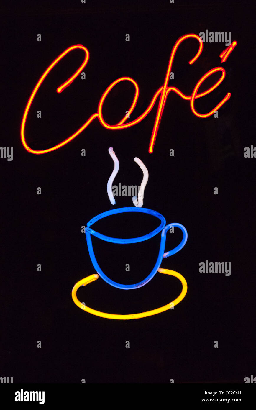 A lighted neon sign in a coffee shop window at night with a neon coffee