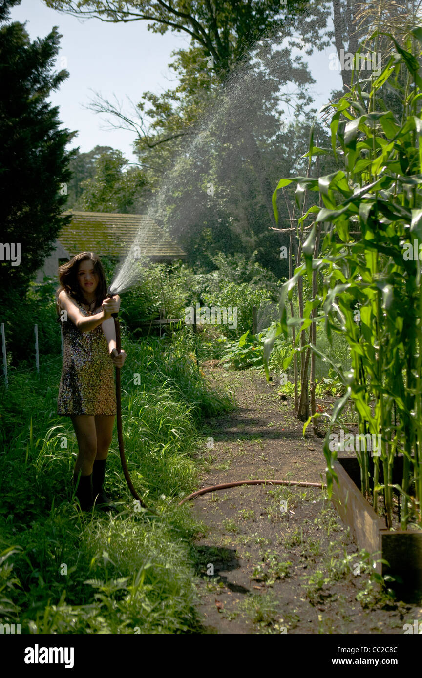Girl watering garden in sequined dress. Stock Photo