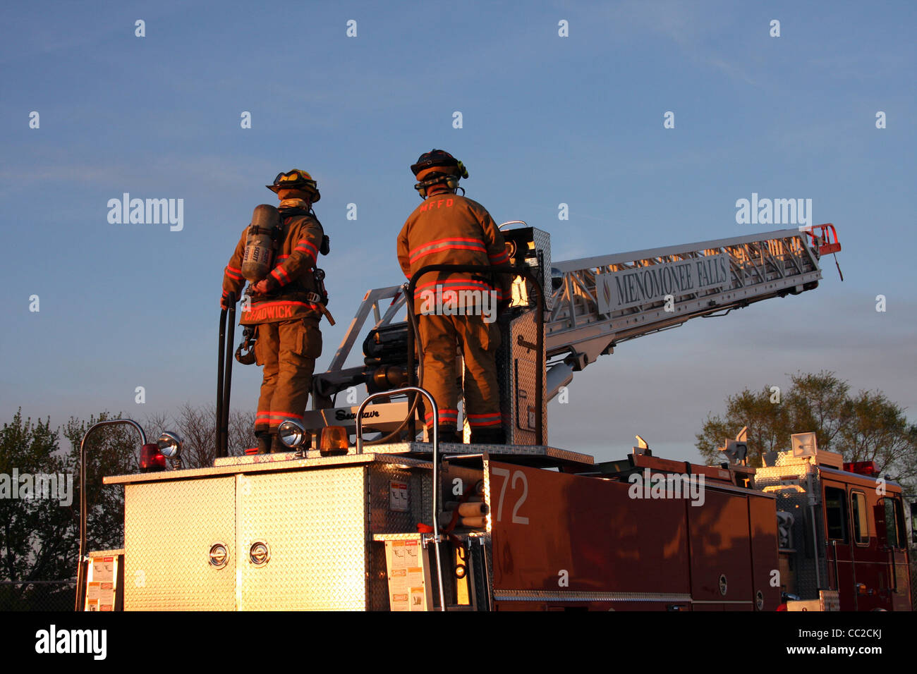Two firefighters working the controls of a ladder truck Stock Photo