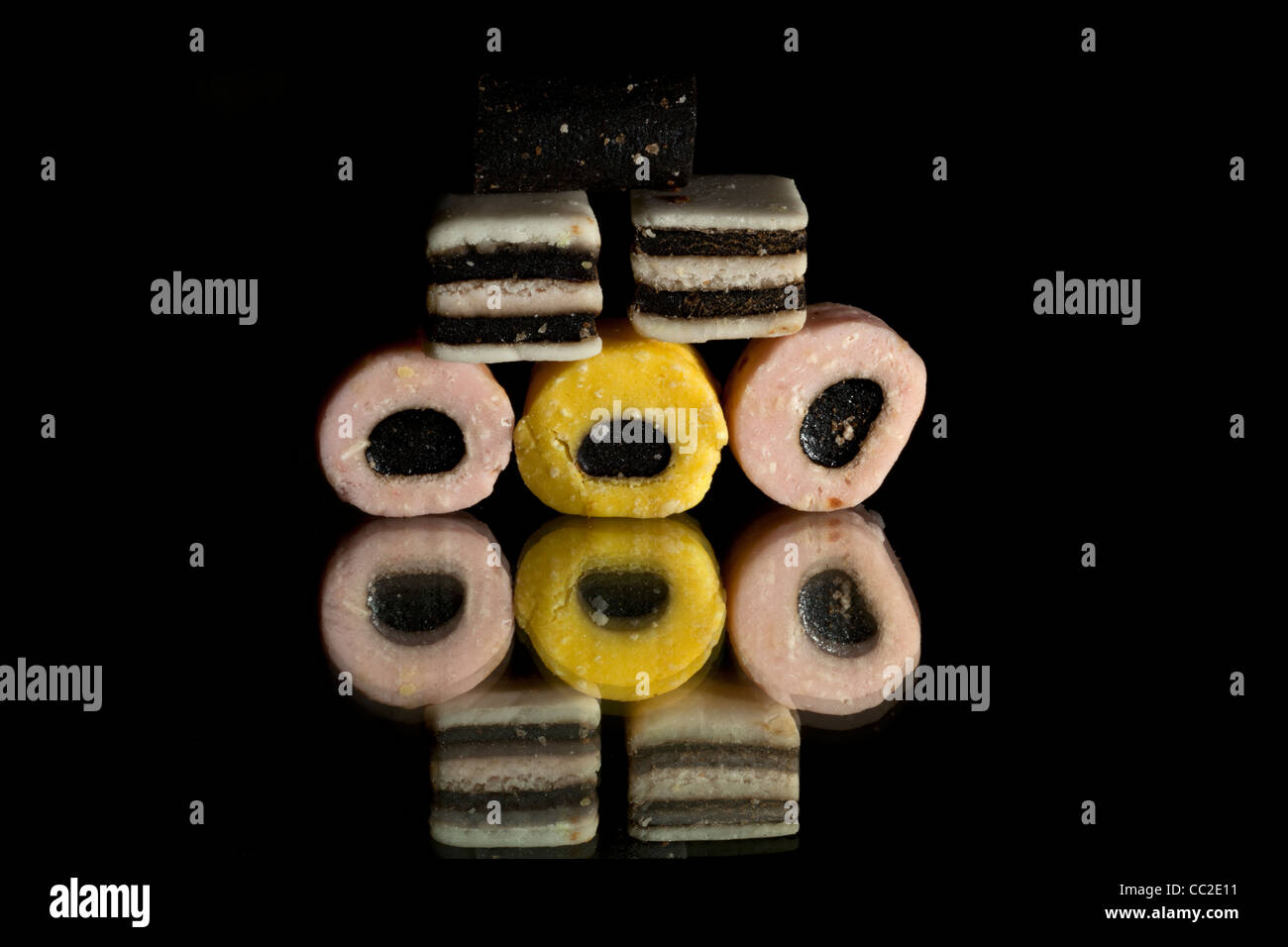 5 pink yellow and black and white liquorice allsorts sweets on a black