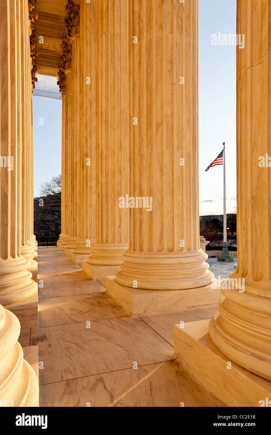 Late afternoon winter sun illuminates the columns of supreme court in Washington in winter with view of US flag Stock Photo