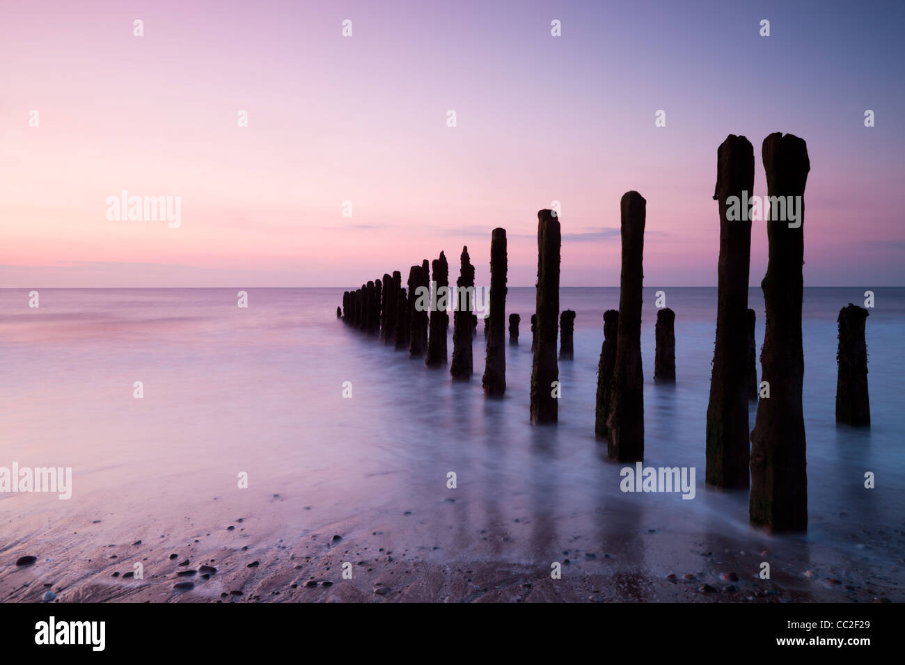 Old sea defences at dawn, smooth water from long exposure. Stock Photo