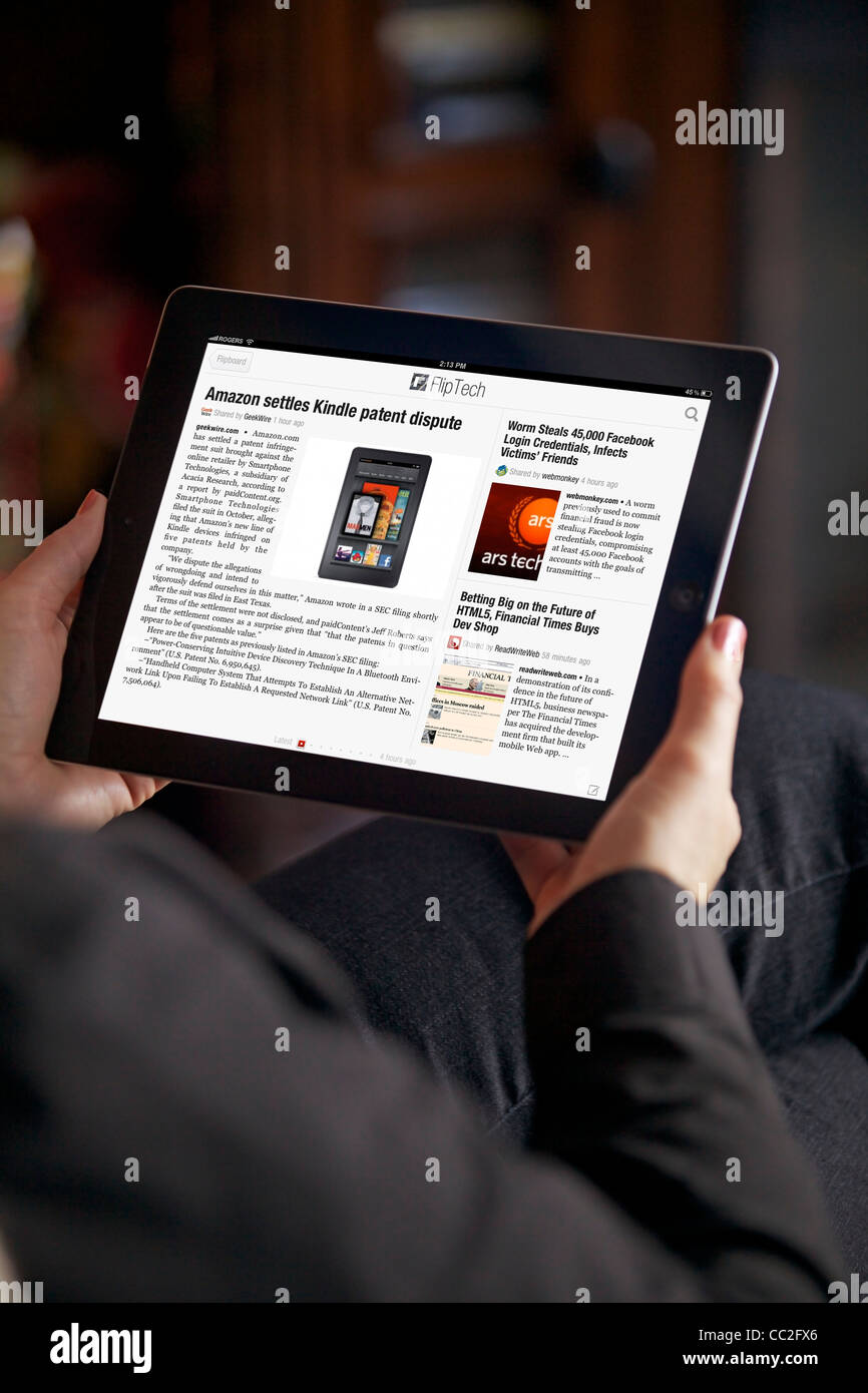 Close up view of a woman relaxing in the living room while reading news from Flipboard app on her iPad 2 Stock Photo