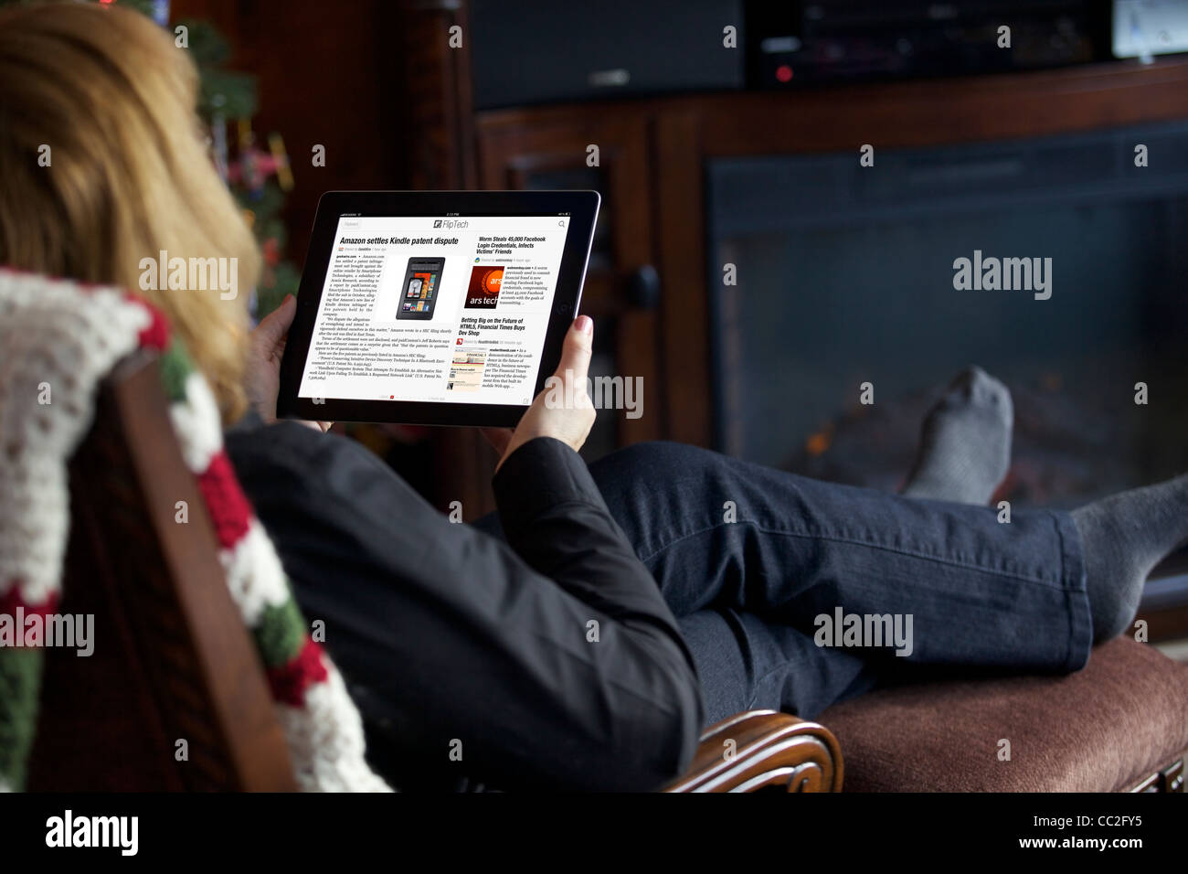 Adult woman relaxing in the living room while reading news from Flipboard app on her iPad 2 Stock Photo