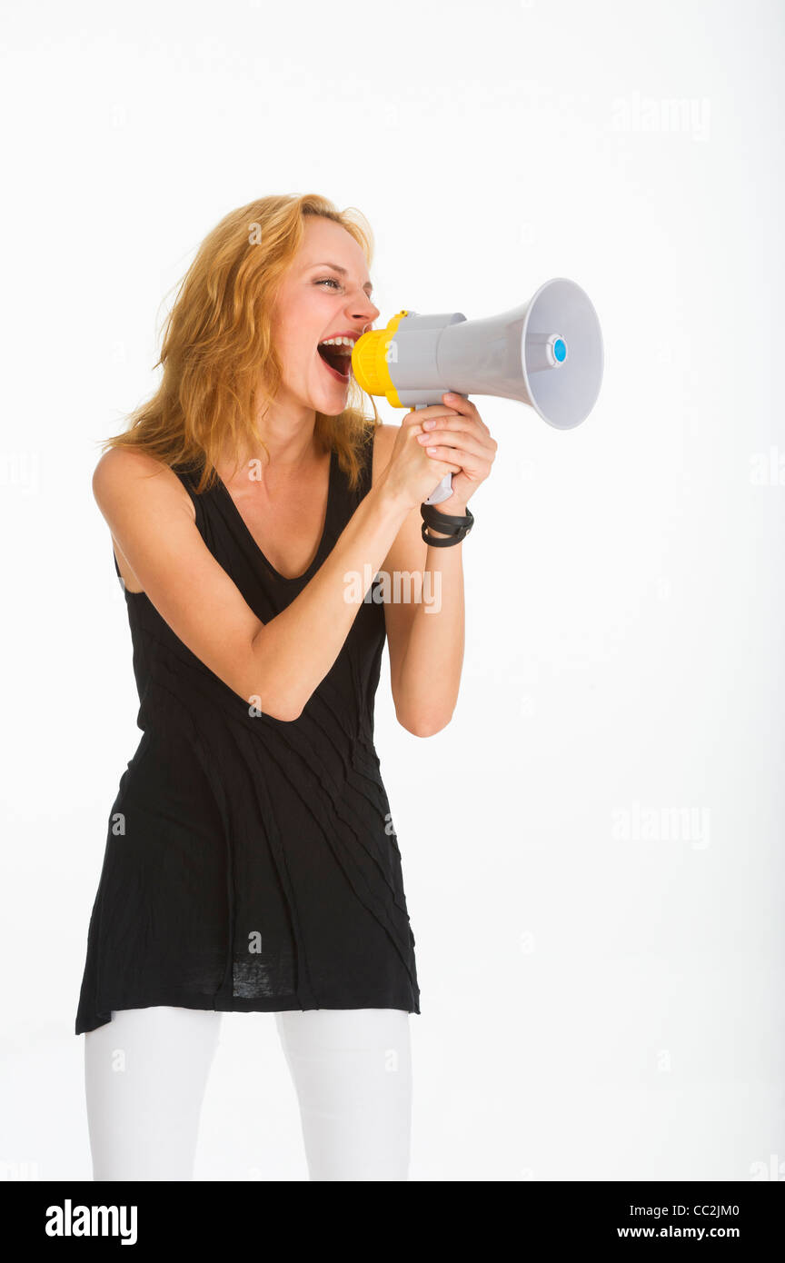 Woman shouting through bullhorn, studio shot Stock Photo
