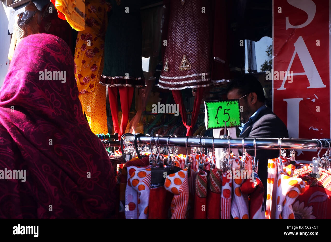 A Muslim woman looks through clothes on sale at a market sale in London's East End Stock Photo