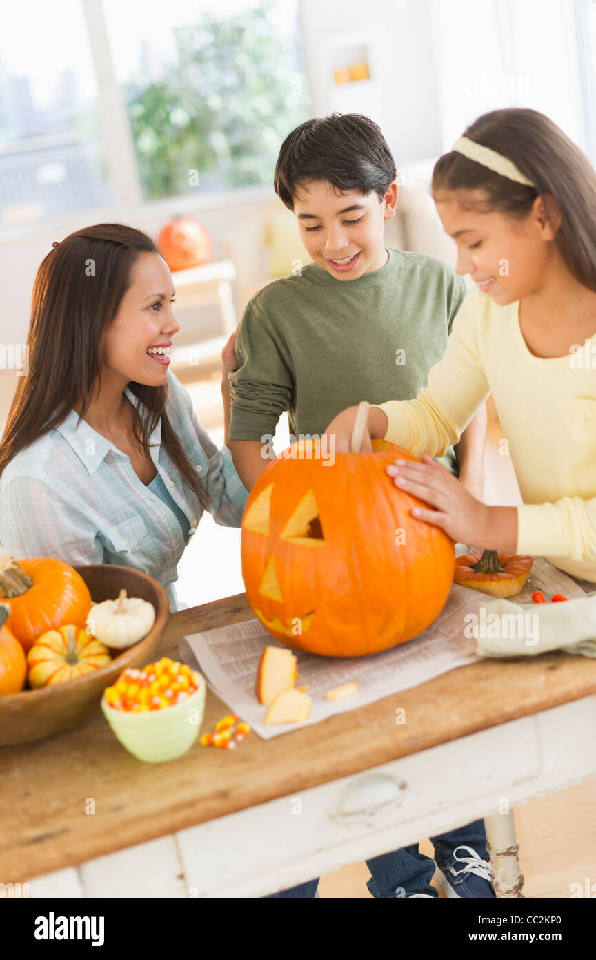 USA, New Jersey, Jersey City, Mother with son (12-13) and daughter (10-11) doing Jack o lantern Stock Photo