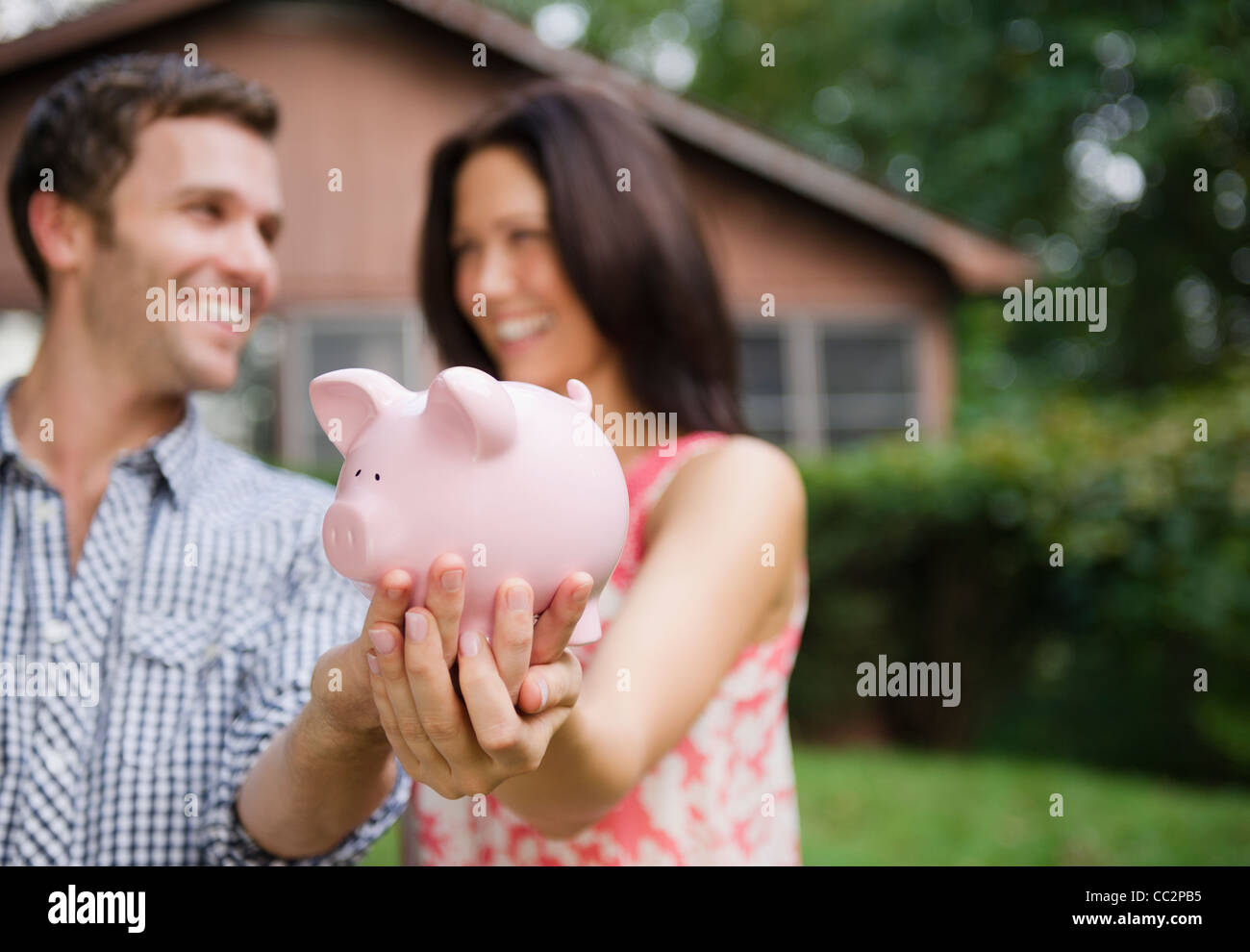 smiling couple holding big piggy bank Stock Photo - Alamy