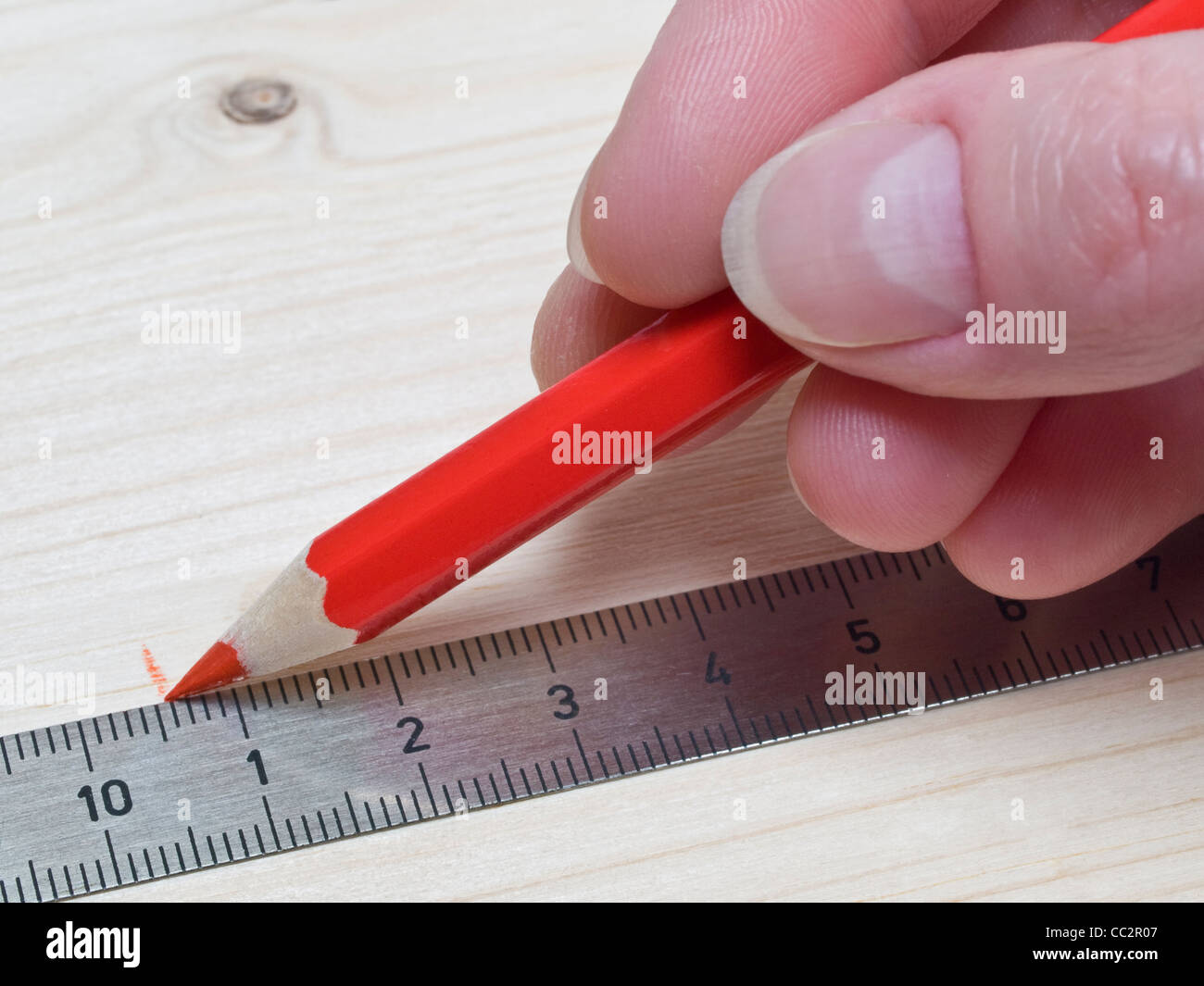 on a piece of wood a point is measured and market with a red colored pencil Stock Photo