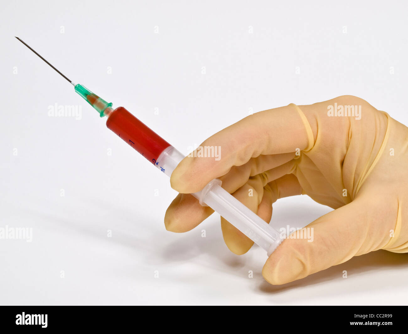a syringe is held in the hand with rubber gloves Stock Photo