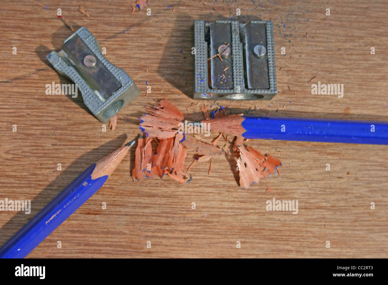 Pencils, pencil sharpeners and shavings on plywood worktop Stock Photo