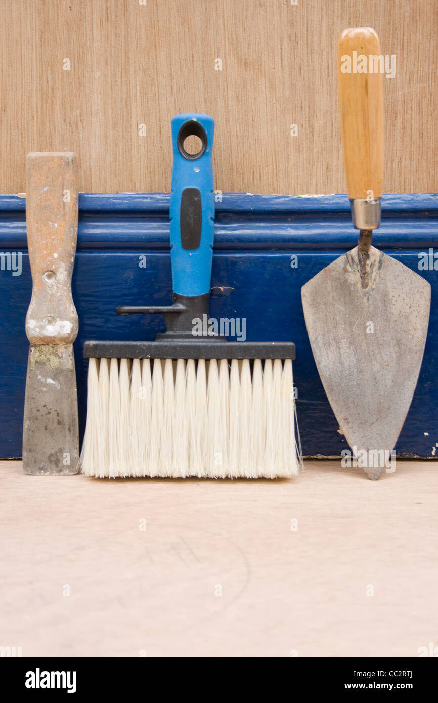 Various hand tools leaning against a skirting board. Stock Photo
