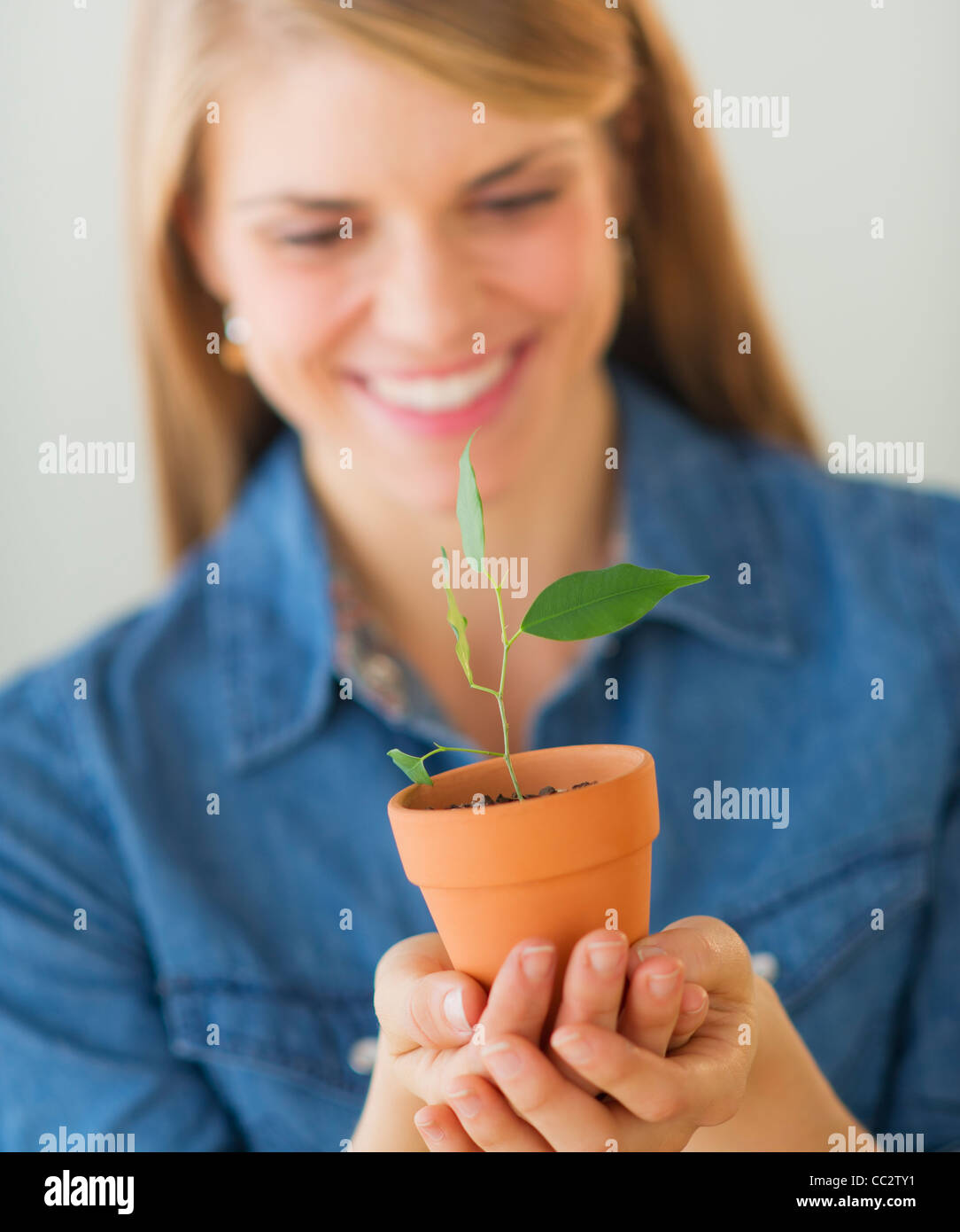 Young woman holding small plant Stock Photo - Alamy