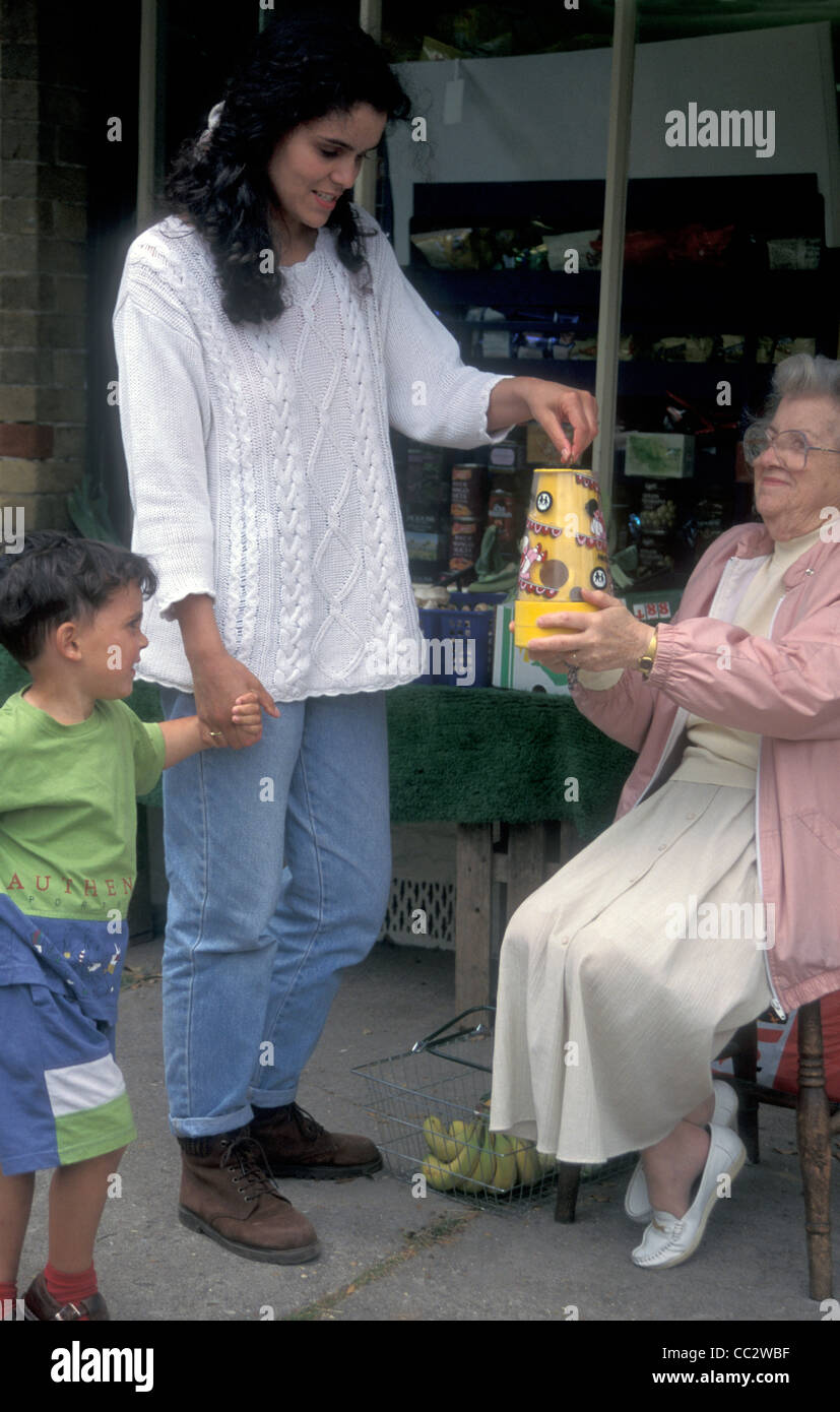 elderly woman sitting outside local grocery store collecting money for charity Stock Photo