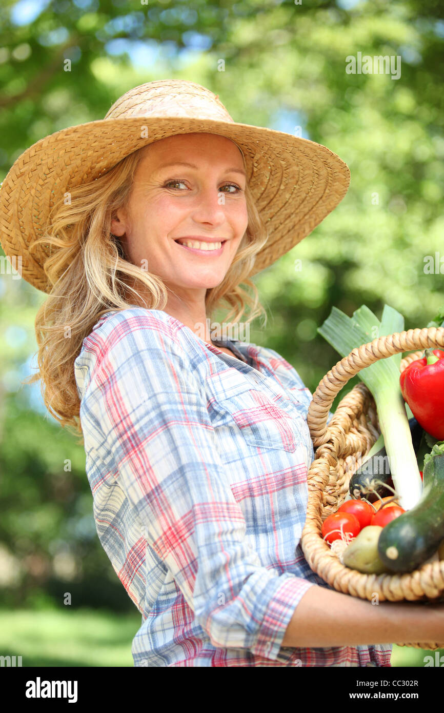 Woman smiling with a straw hat holding basket of vegetables Stock Photo ...