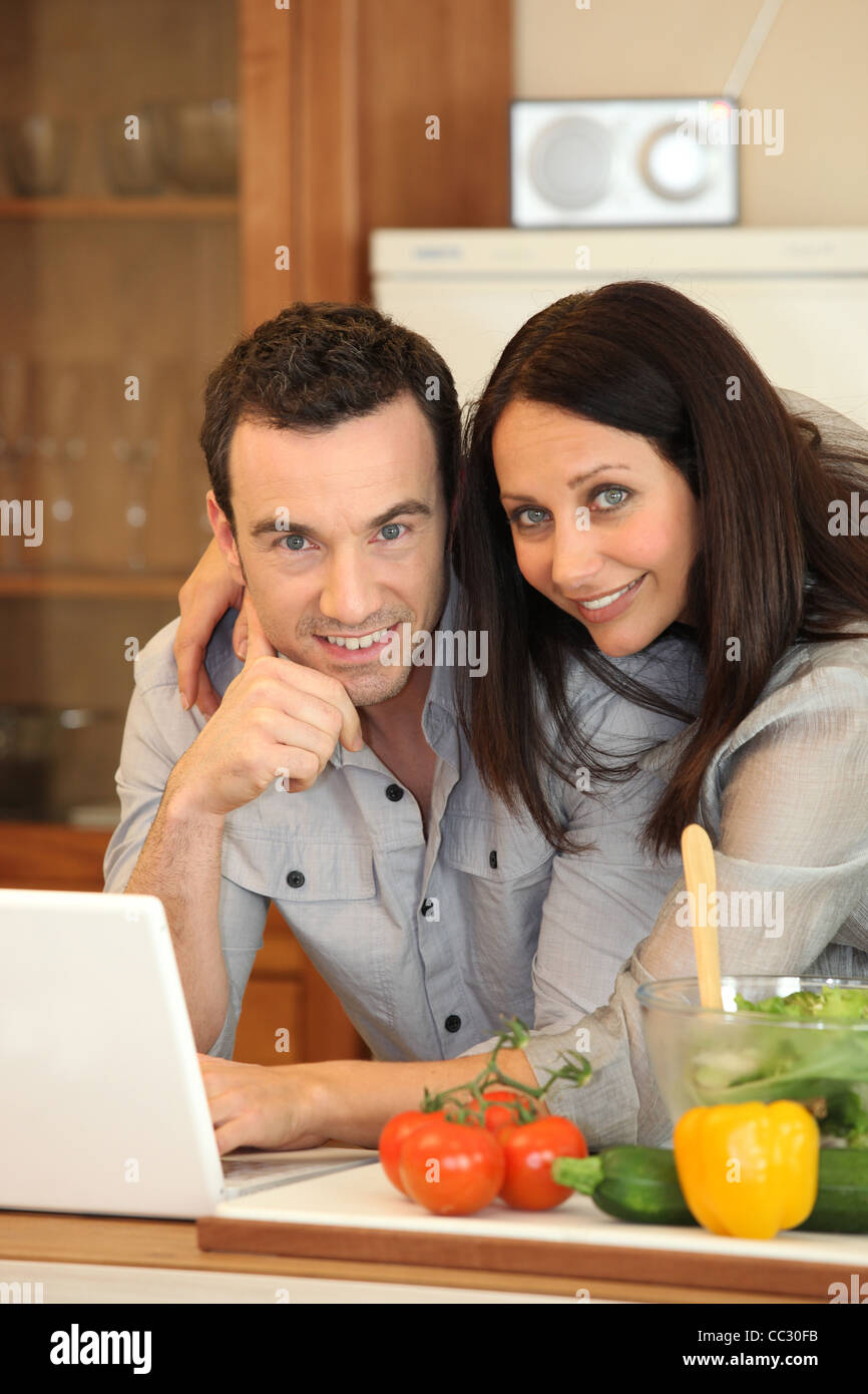 Couple in kitchen on laptop Stock Photo - Alamy