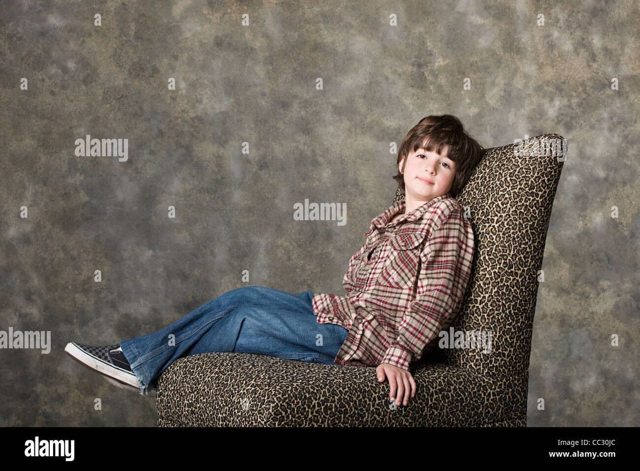 Portrait of boy (6-7) sitting on chair, studio shot Stock Photo