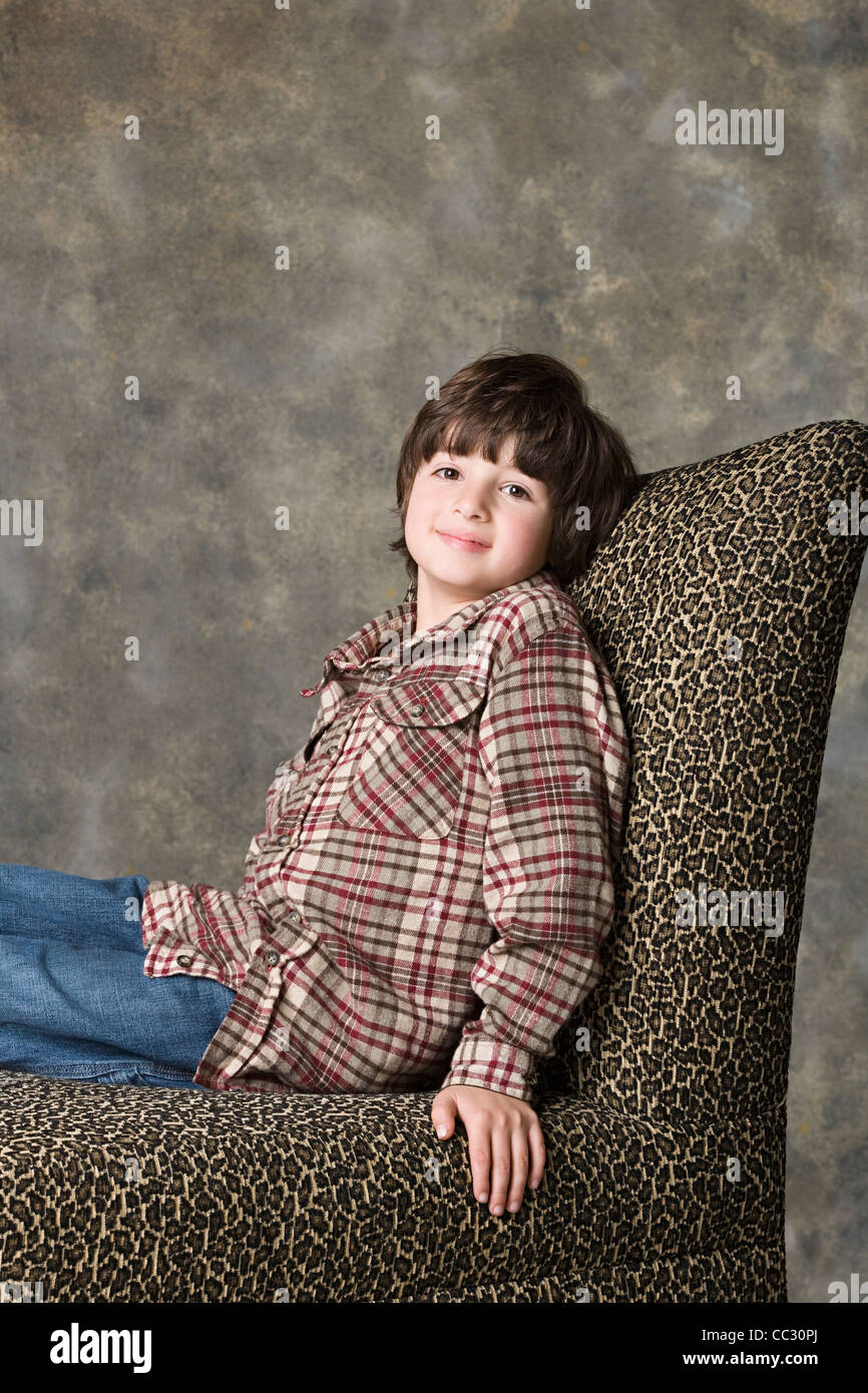 Portrait of boy (6-7) sitting on chair with animal print, studio shot Stock Photo