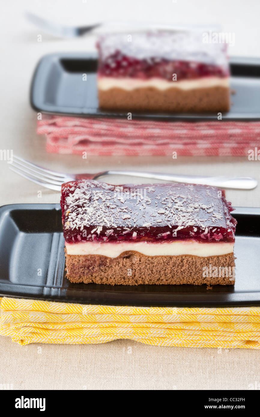 Two slices of cake, chocolate with cream and fruit topping Stock Photo