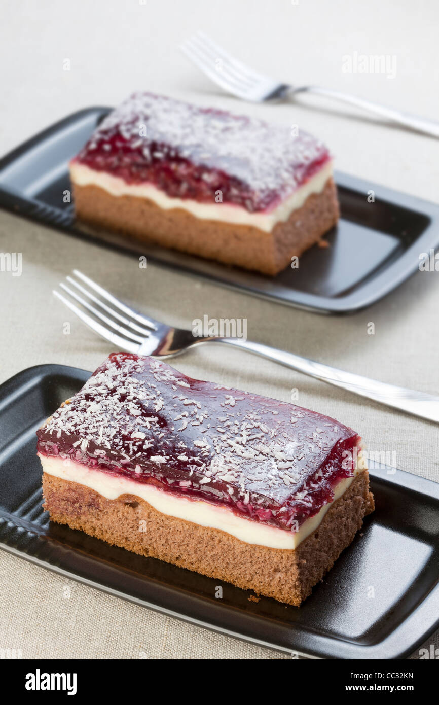 Two slices of cake, chocolate with cream and fruit topping Stock Photo
