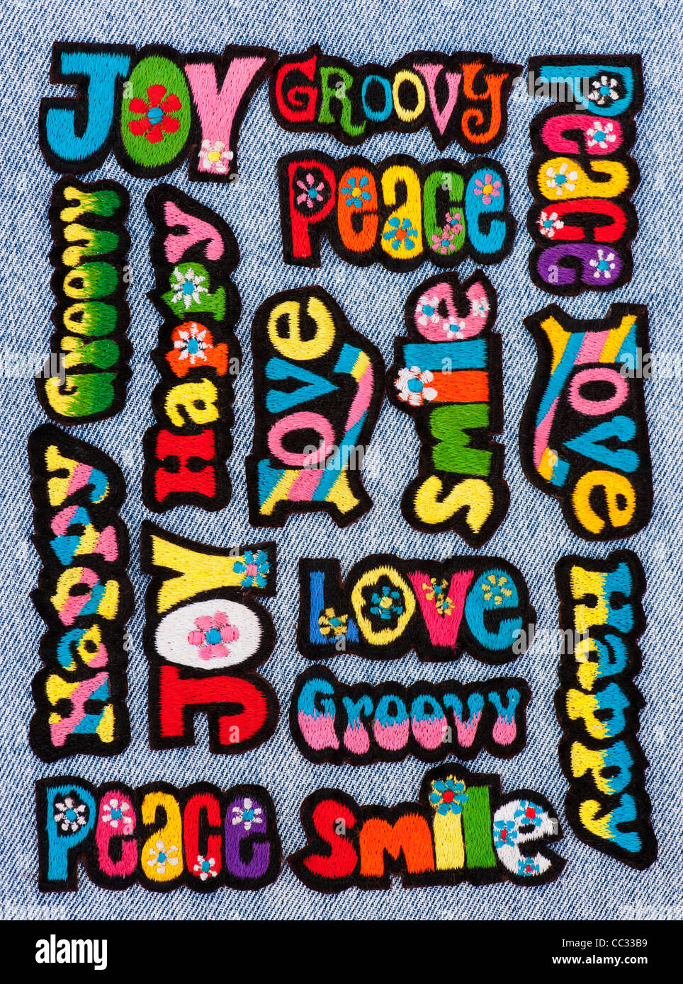 Embroidery iron on patches of Multicoloured Love, Peace, Happy, Smile, Joy and Groovy words on a denim jean background Stock Photo