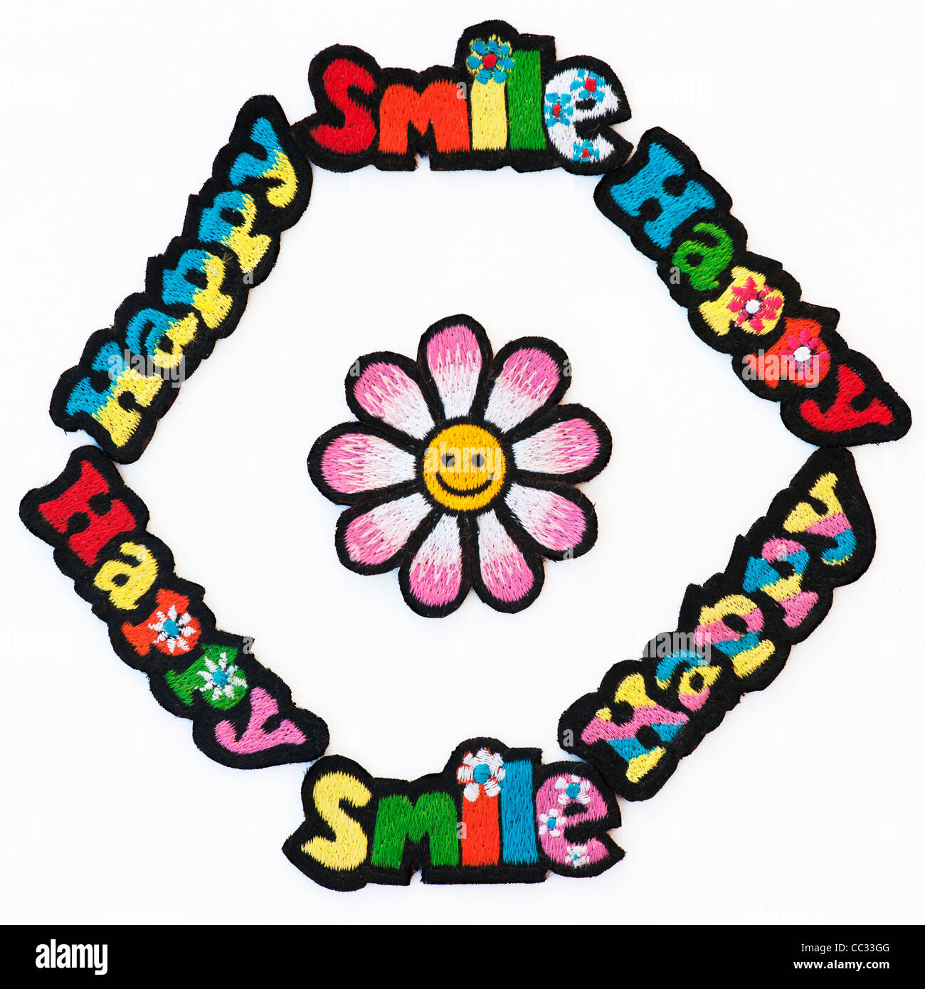 Embroidery iron on patches of Multicoloured Happy and Smile words with a smiley face flower on a white background Stock Photo