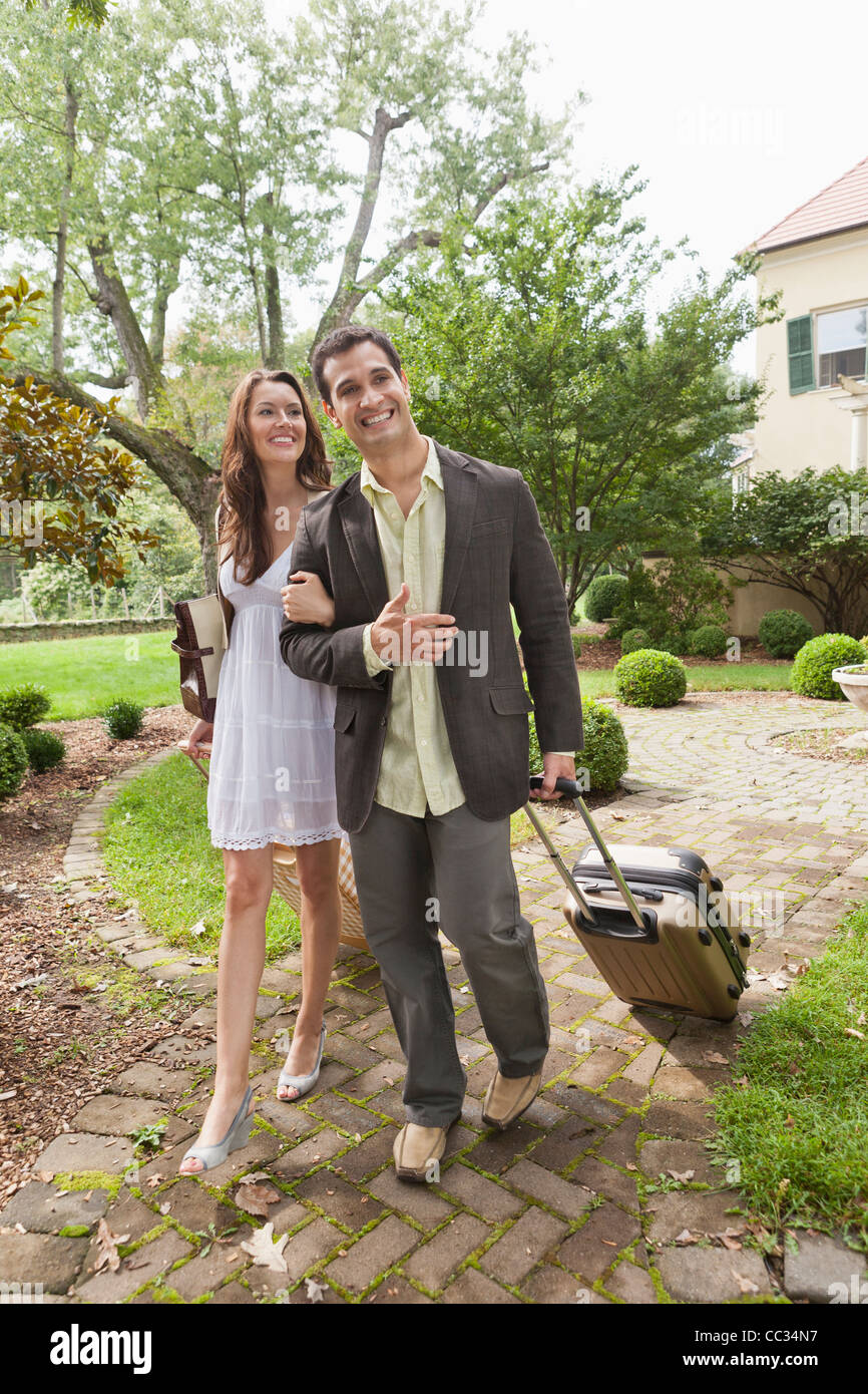 USA, New Jersey, Smiling couple with suitcase walking on footpath Stock Photo