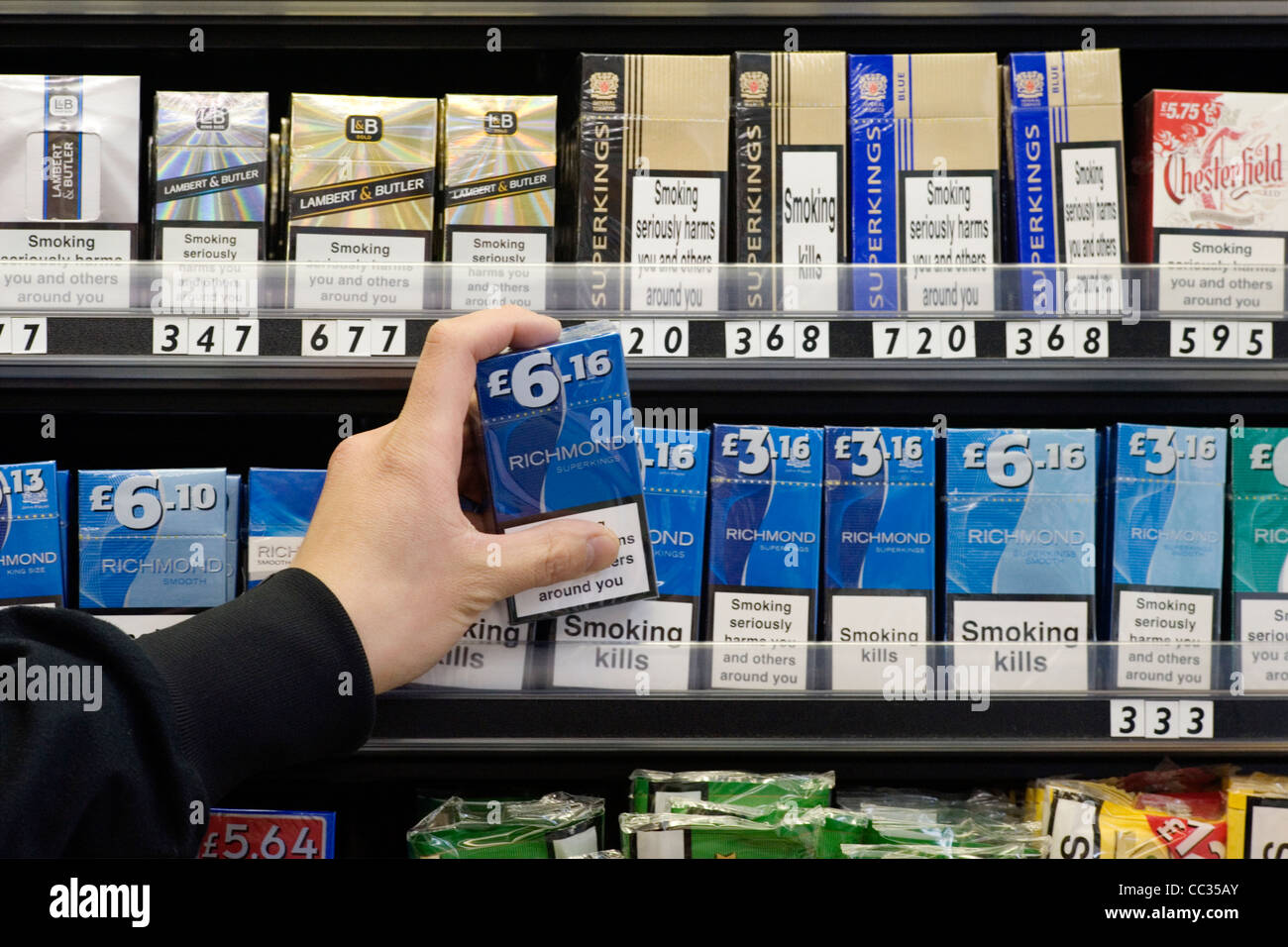 shopkeeper taking a packet of cigarettes from display Stock Photo