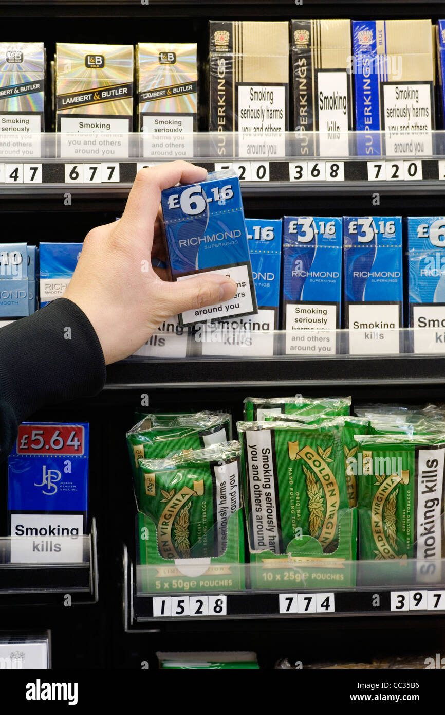 shopkeeper taking a packet of cigarettes from display Stock Photo