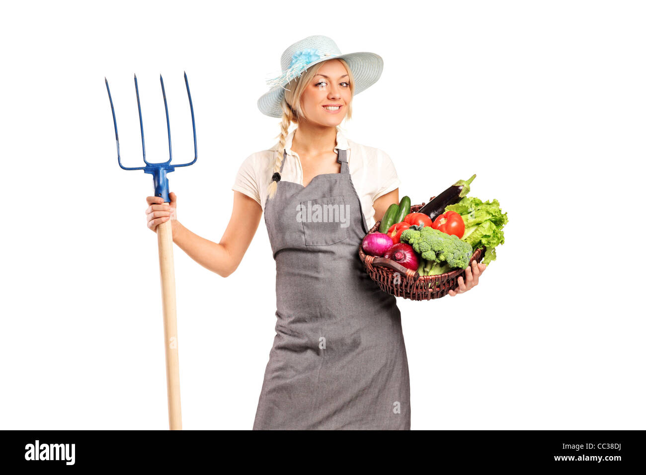 A female farmer holding a pitchfork and basket with vegetables Stock ...