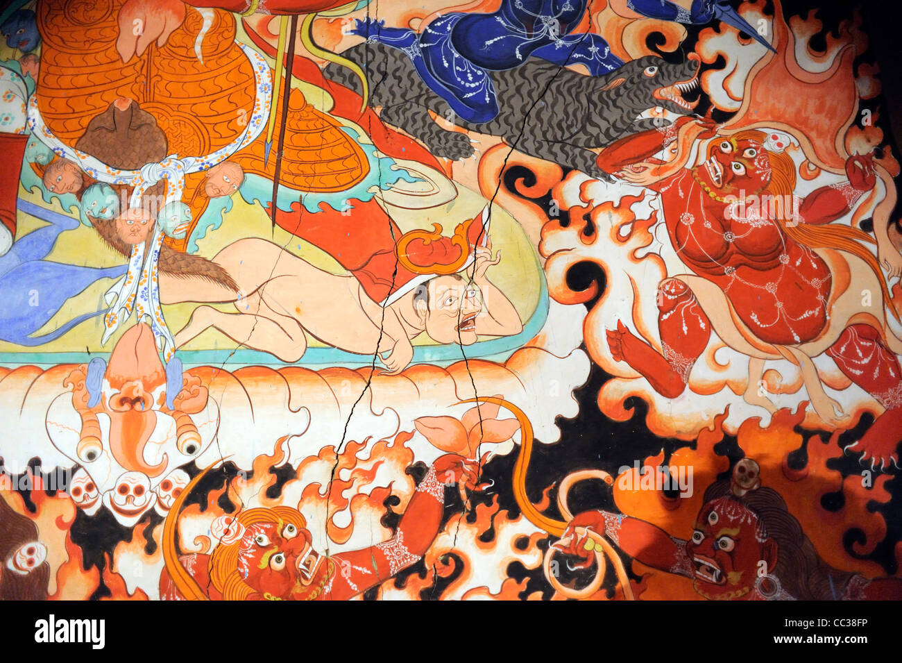 A wall painting in traditional Tibetan buddhist style shows a human under the foot of a wrathful protective being Stock Photo