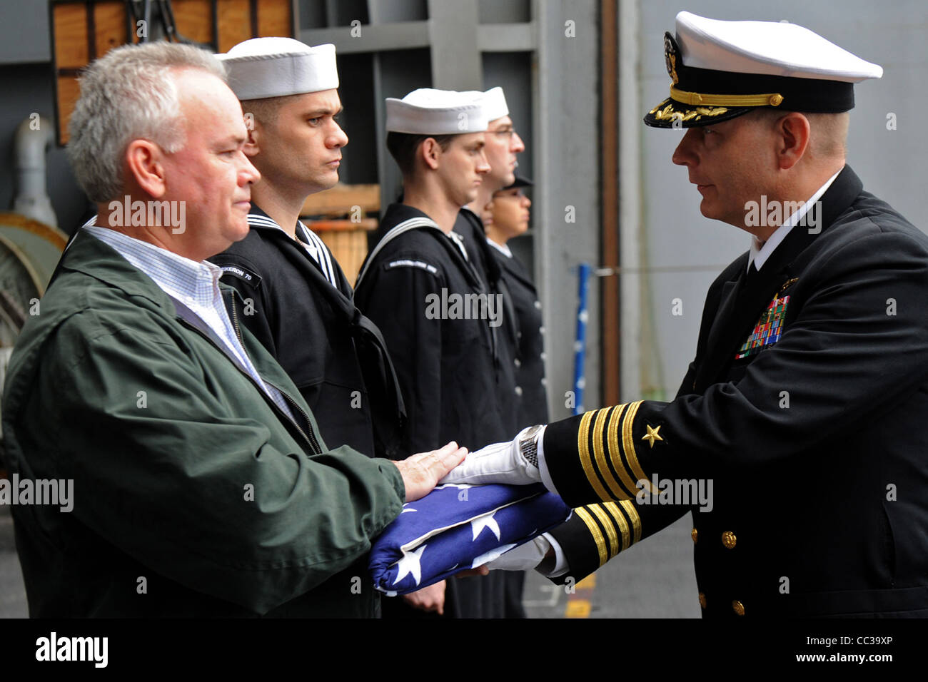 Presenti the national ensign to Robert Moye, the son of retired Navy Cmdr. William Moye, during a burial at sea ceremony. Stock Photo