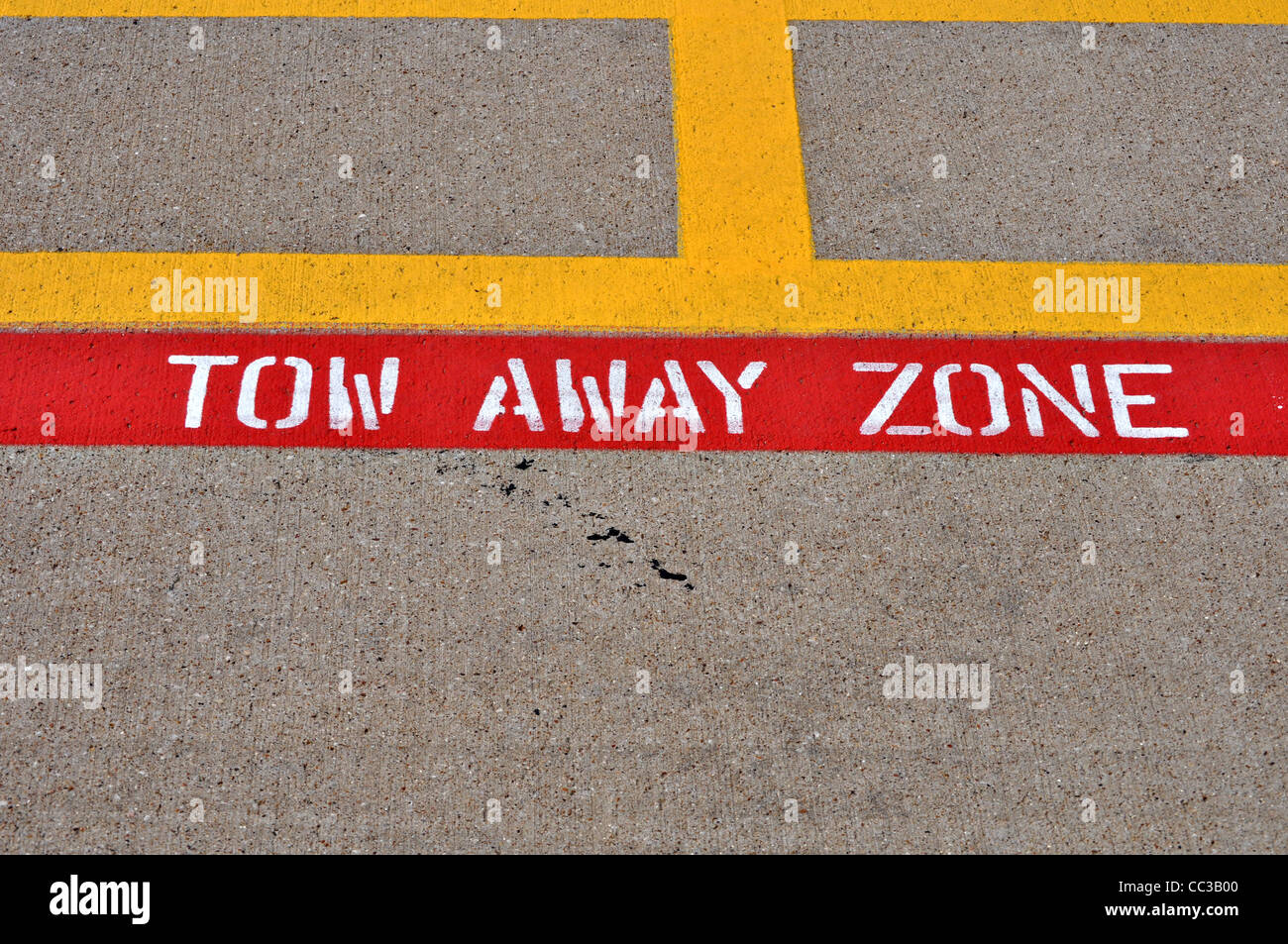 A painted tow away zone sign is painted on cement parking lot. Stock Photo