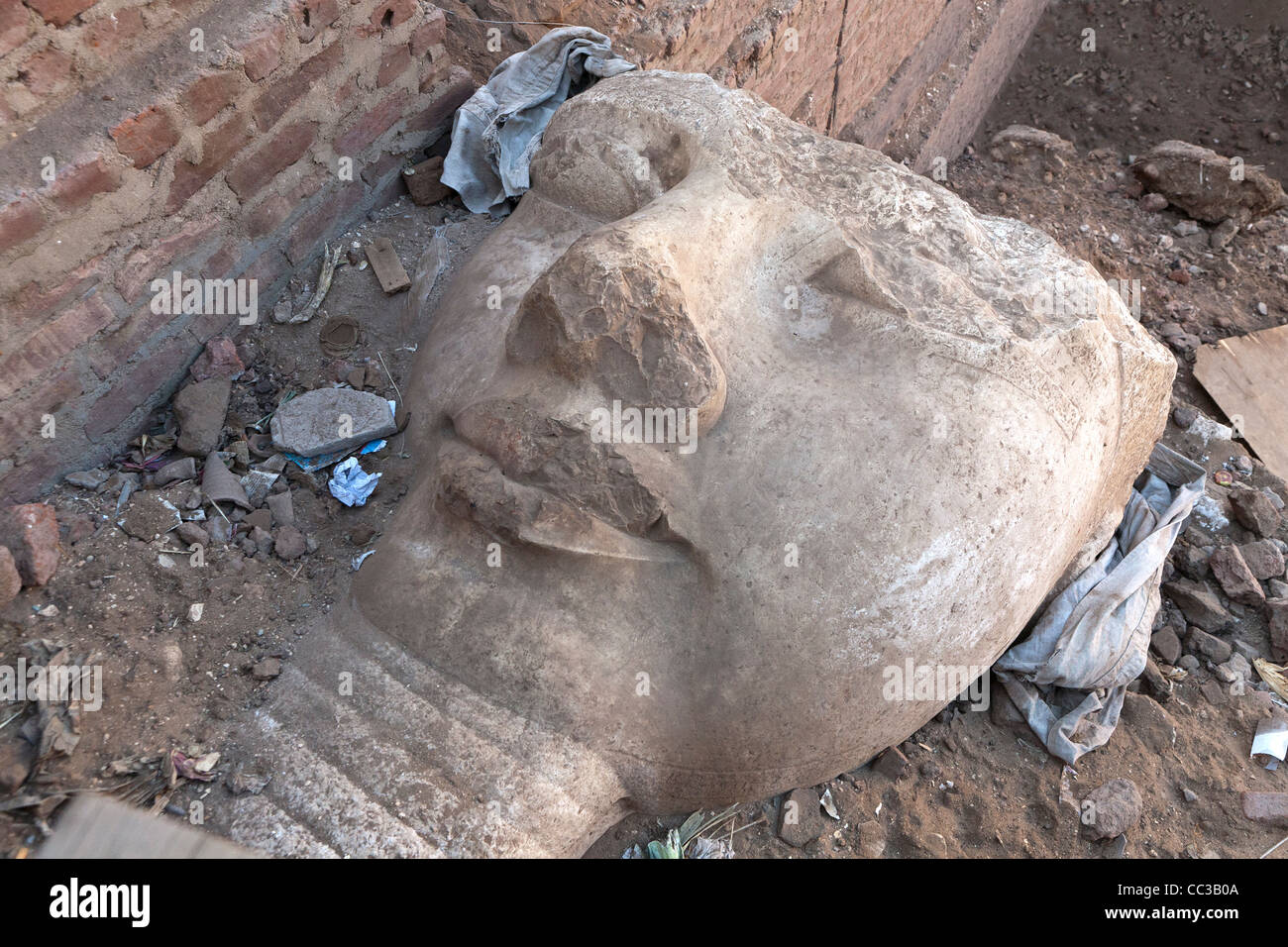 Exposed statue head at site of an unexcavated Ramesside temple running under local cemetery at Akhmim near Sohag, Middle Egypt. Stock Photo